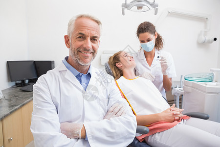牙医与助手和病人在后面笑着看镜头高清图片