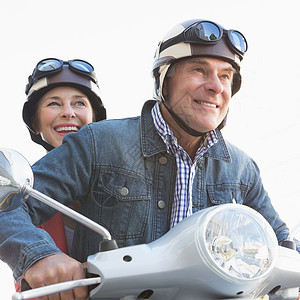 骑摩托车的老年快乐情侣阳光休闲金发女郎方式男性助力车城市生活晴天浅色车辆背景图片