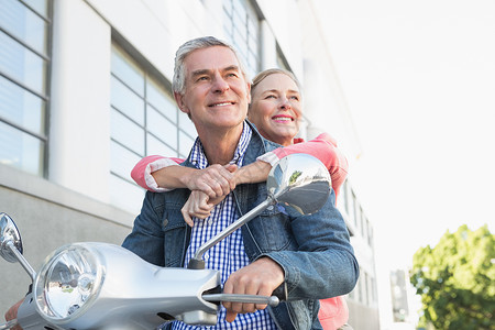 骑摩托车的老年快乐情侣夫妻金发女性交通助力车金发女郎感情浅色闲暇城市生活背景图片