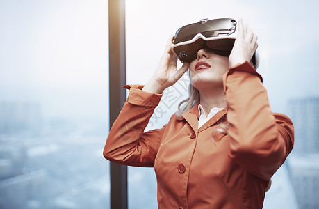 办公室里戴着虚拟现实耳机的女人眼镜上网齿轮外套电脑高科技技术娱乐女士游戏背景图片