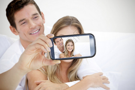情侣在智能手机上自拍异性男性夫妻丈夫沙发情感技术女性动画女朋友亲热高清图片素材