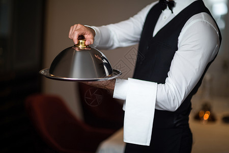 手持托盘的英俊服务员餐厅男性衬衫毛巾马甲酒店领结男人服务背景图片