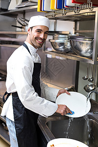 清理盘子男人做菜的英俊雇员职员洗碗机肥皂职业厨房盘子男人制服龙头手套背景