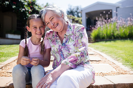 祖母和孙女坐在花园的花园里女性服装老年晴天感情快乐女士女孩家庭闲暇背景图片