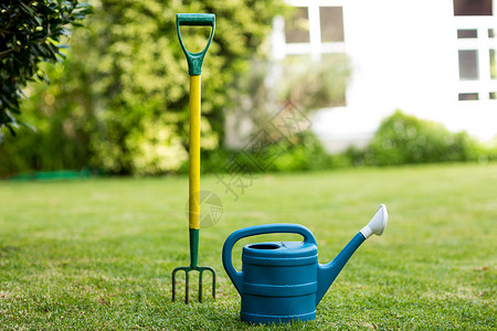 蓝色浇水壶在院子里特写雷克和水罐背景