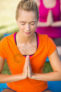 妇女做瑜伽运动服绿地晴天练习眼睛冥想公园沉思金发姿势背景图片