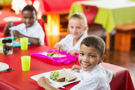 儿童在学校食堂休息时间吃午餐的儿童人数小学生女孩学校盘子女学生瞳孔桌子教育食堂知识午餐时间高清图片素材