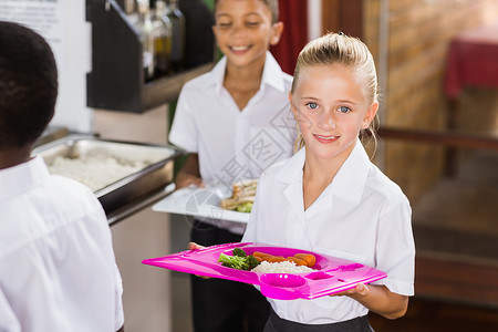 在学校食堂里拿着餐盘的微笑女学生男生高清图片素材