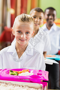 女学生在休息时间吃午饭的肖像快乐幼儿园学校蔬菜托盘午餐孩子们男性教育女性微笑高清图片素材