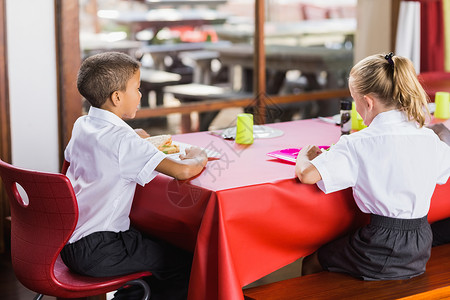 在食堂吃午餐时穿校服的男男女女蔬菜知识学校食物童年教育男性孩子们桌子瞳孔休息高清图片素材
