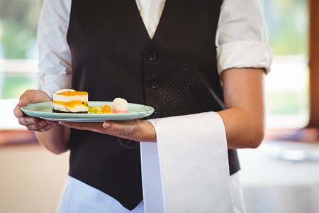 服务员拿着一个带蛋糕的盘子食品女性工作服务餐饮马甲零售毛巾行业美食背景图片