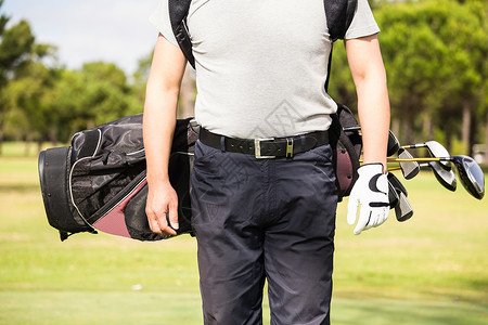 身穿高尔夫球袋的人的中流体晴天高尔夫手套生活方式运动员爱好假期阳光休闲活动背景