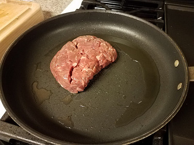 炉灶煎锅中的生牛肉和油背景图片