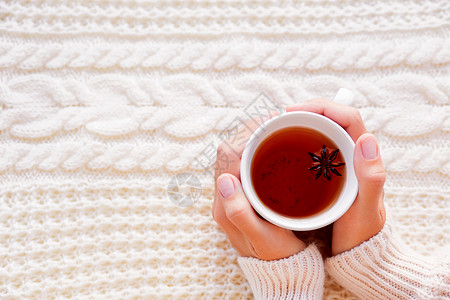 妇女们端着一杯加了八角的热茶 美丽的织物背景与针织图案 舒适的早晨在家星星温暖毛衣饮料香料杯子背景图片