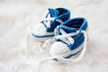 小婴儿鞋 为新生男孩或新生儿首届运动鞋衣服展示新生钩针白色针织男生母性按钮女孩背景