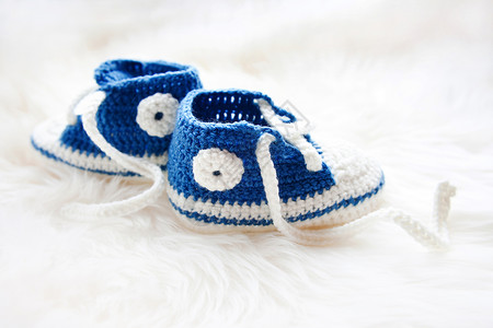 小婴儿鞋 为新生男孩或新生儿首届运动鞋母性衣服父母钩针蓝色白色孩子按钮展示女孩背景