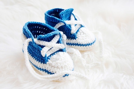小婴儿鞋 为新生男孩或新生儿首届运动鞋女孩针织钩针男生展示靴子蓝色手工白色母性背景