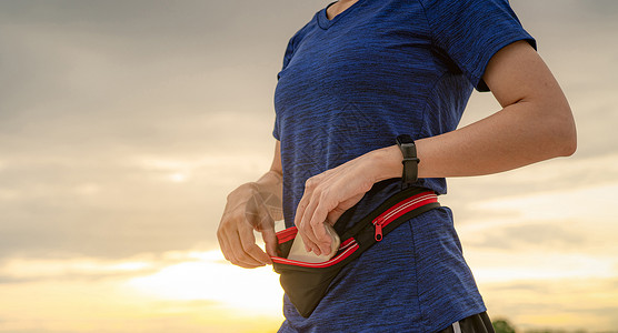 小手机包素材年轻亚洲女性在跑步前用腰包装智能手机手腕活动锻炼技术手表慢跑者女孩速度日出教练背景