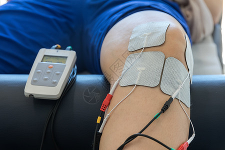 膝盖上的电子疗法用来治疗疼痛 有选择的焦点机器身体皮肤海浪脊椎脉冲生理学功能性肌肉宽慰背景图片
