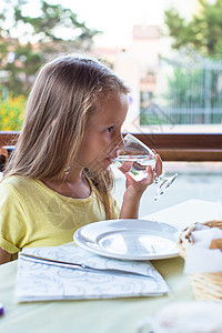 可爱的小女孩在早餐和饮用水中吃早餐小吃高清图片素材