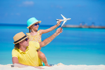 年轻男子和小女孩在海滩上拥有小飞机的小型飞机孩子行动婴儿空气爸爸活动家庭教育自由幸福背景图片