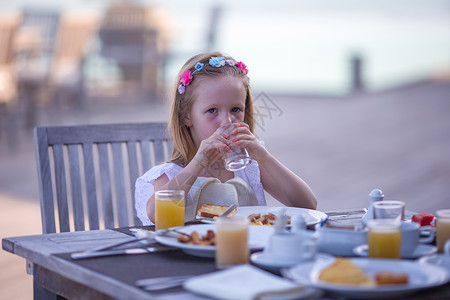 可爱的小女孩在户外咖啡厅吃早餐咖啡店金发杯子蜂蜜孩子快乐食物餐厅假期眼睛快乐的高清图片素材