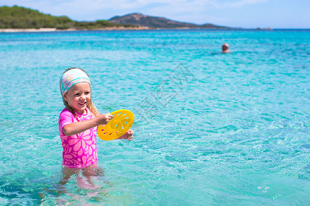 热带度假时玩飞盘的小可爱女孩儿游泳海滨乐趣假期享受海岸喜悦幸福海洋孩子背景图片