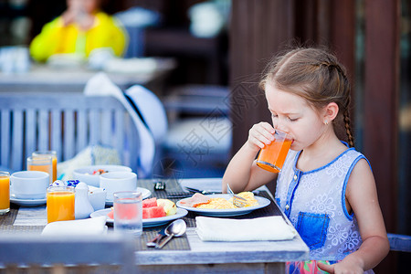 可爱的小女孩 在户外咖啡厅吃早餐喝果汁咖啡店高清图片素材