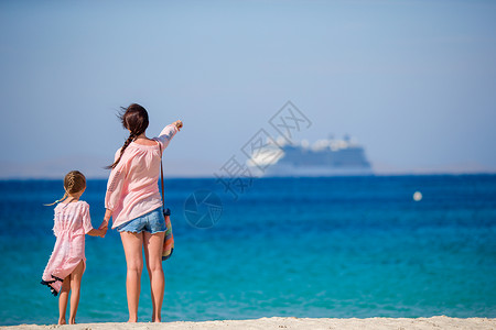 女孩和船年轻美丽的母亲和可爱的小女儿 在热带海滩的热带沙滩上看着大海背景