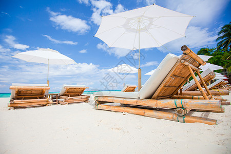 外来热带白色沙沙滩上的海滩床和白色雨伞高清图片