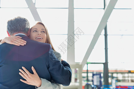 生意夫妇在机场重新团聚和拥抱对方的一对情侣女性飞机场会议旅行夫妻商业套装商界职业正装背景图片
