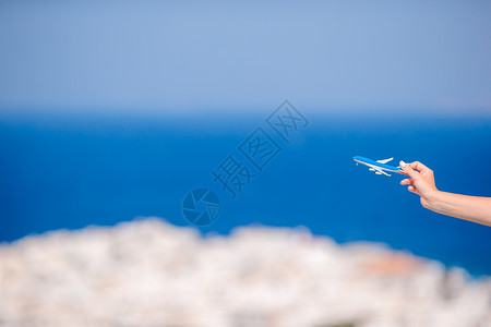 折飞机女孩拥有玩具飞机的旅游女游客手握着古希腊村背景手工自由空气旅行假期乐趣游戏工艺活动女士背景