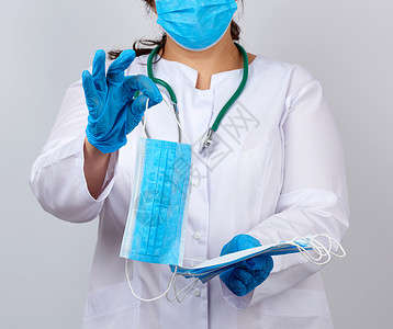 穿着白外套和面罩的女医生拿着一堆保护物护士保健蓝色外科职业实验室疾病治疗工人临床手高清图片素材