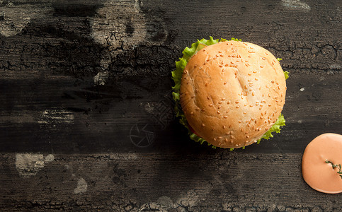 木质表面的芝士汉堡沙拉午餐叶子牛肉黑色小吃木头芝麻面包烧烤背景图片