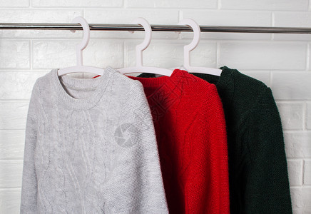 一排毛衣衣服挂在衣架上 穿红色 绿色和黑兰格的羊毛衣湿气零售织物针织品外套壁橱运动衫羊毛球衣衬衫背景