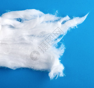 蓝色背景上边缘撕裂的白色羊毛空白柔软度材料纺织品背景图片