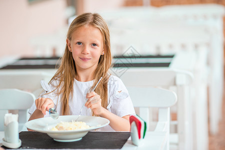 可爱的小女孩在户外咖啡厅吃晚饭面条幸福盘子咖啡店眼睛女儿食物晚餐胡椒食欲健康高清图片素材