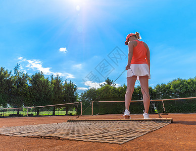 在一个户外网球场上的柳橙粘土女士网球运动天空黏土地面游戏扫帚闲暇运动员背景图片