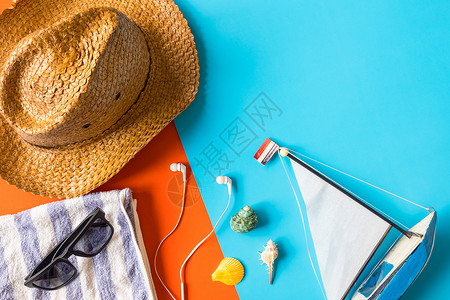海滩饰品的顶端视图 在多彩背景上贝壳太阳镜假期橙子耳机旅行配饰帽子蓝色毛巾背景图片