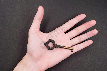 男性手持黑色背景的金属钥匙背景图片