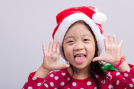 孩子在圣诞服装与圣诞老人的帽子工作室微笑童年快乐戏服女孩红色喜悦裙子白色背景图片