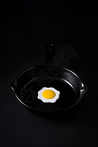 里面有鸡蛋的黑煎锅白色小样蛋黄食物陶器厨房平底锅石板背景图片