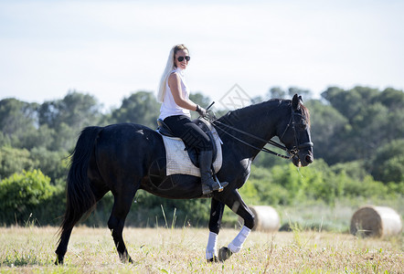 骑马的女童和女童训练骑术动物活动黑色运动头盔女孩骑士闲暇背景图片