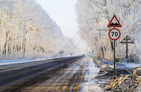 路牌和被雪覆盖树木包围的公路高清图片