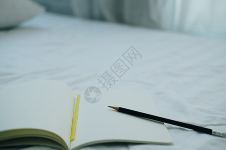 白床垫上的笔记本和铅笔白色背景图片