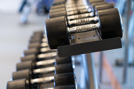 健身房架架上闭合一排金属哑铃锻炼身体架子建筑举重权重杠铃重量肌肉训练背景图片