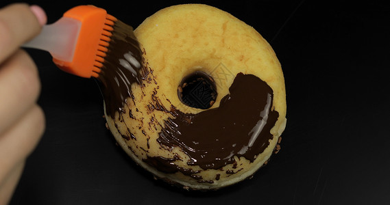 黑巧克力甜甜圈美味的融化深巧克力糖浆 在黑本底甜甜甜圈上散布背景