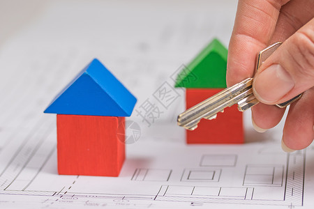 住房负担能力的概念蓝色玩具蓝图盒子钥匙红色绿色构造木头房子背景图片