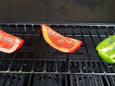 在烧烤炉上烹饪绿辣椒和红辣椒午餐绿色烧烤蔬菜炙烤红色背景图片