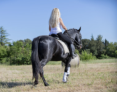 骑马的女童和女童女孩训练动物黑色骑士骑术活动闲暇运动头盔背景图片